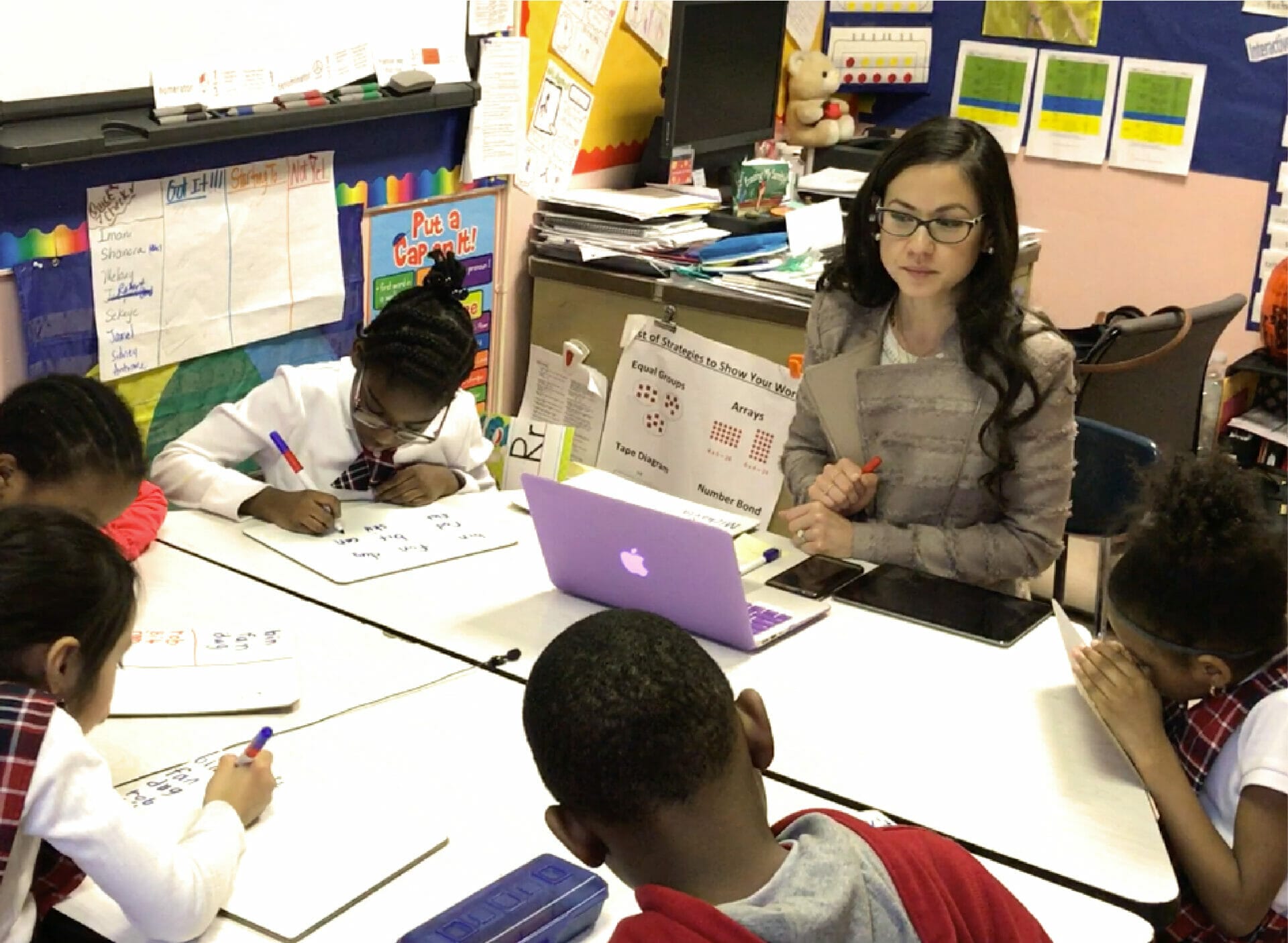 A teacher working with five students around a table