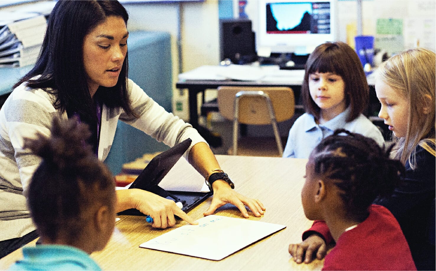 A teacher working with four students around a table