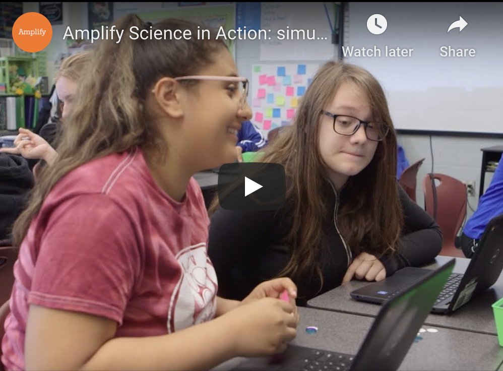 Two students, one smiling, working on laptops in a classroom during a science lesson, with a paused educational video titled 'amplify science in action' on screen.