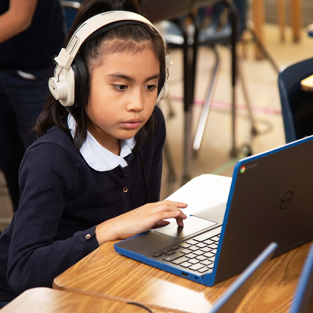 A student wearing headphones and using a laptop