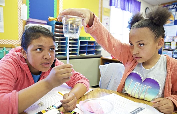 Students observe beaker during science experiment