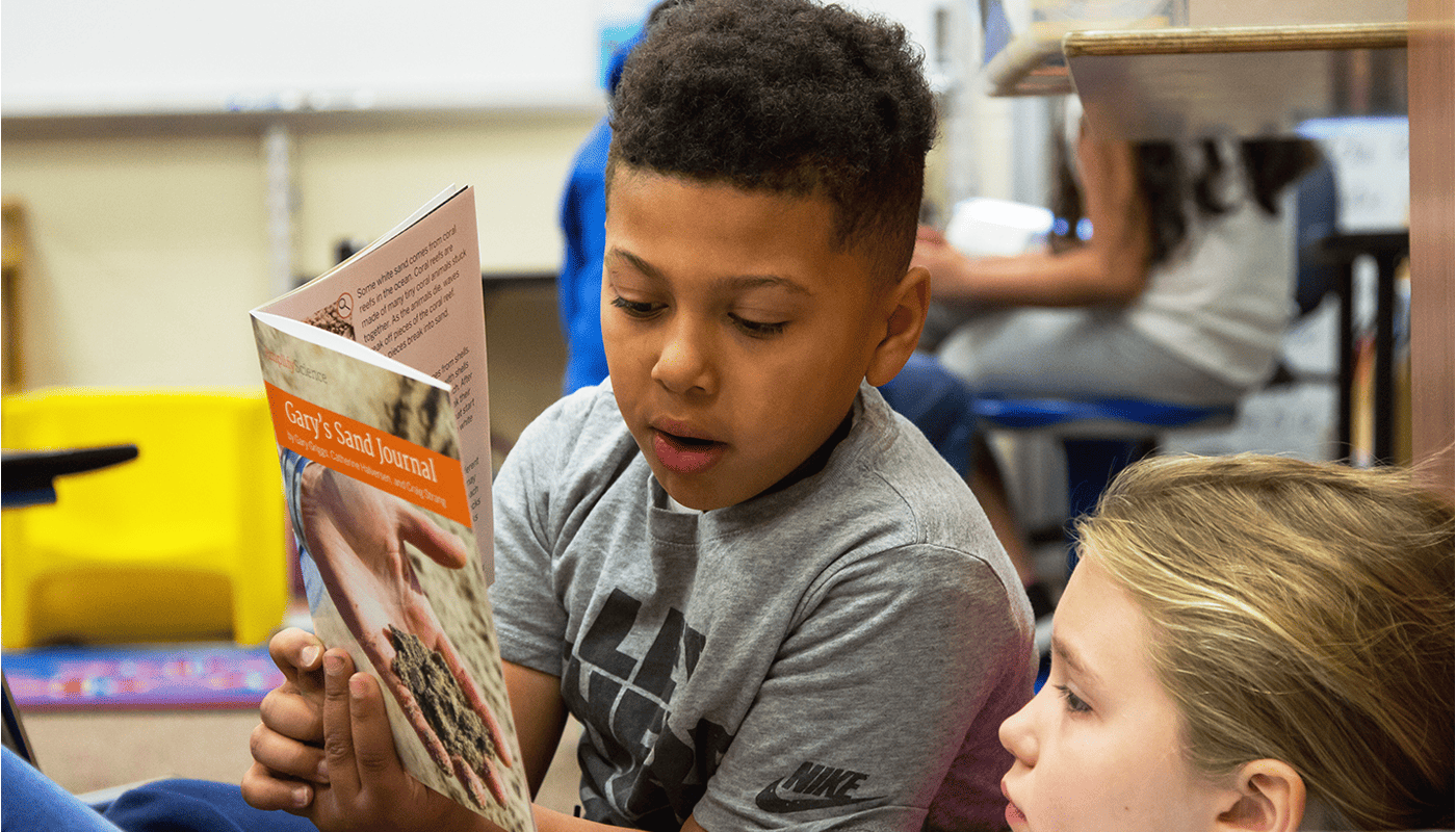 science or literacy instruction two elementary students read a book together in science class