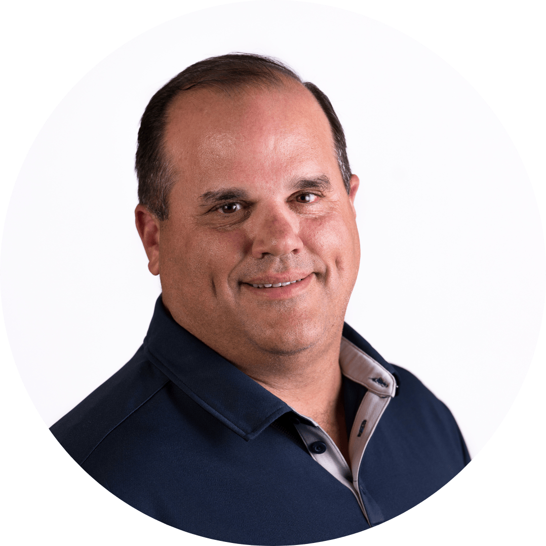 Headshot of a smiling middle-aged man in a blue shirt, set against a white background.