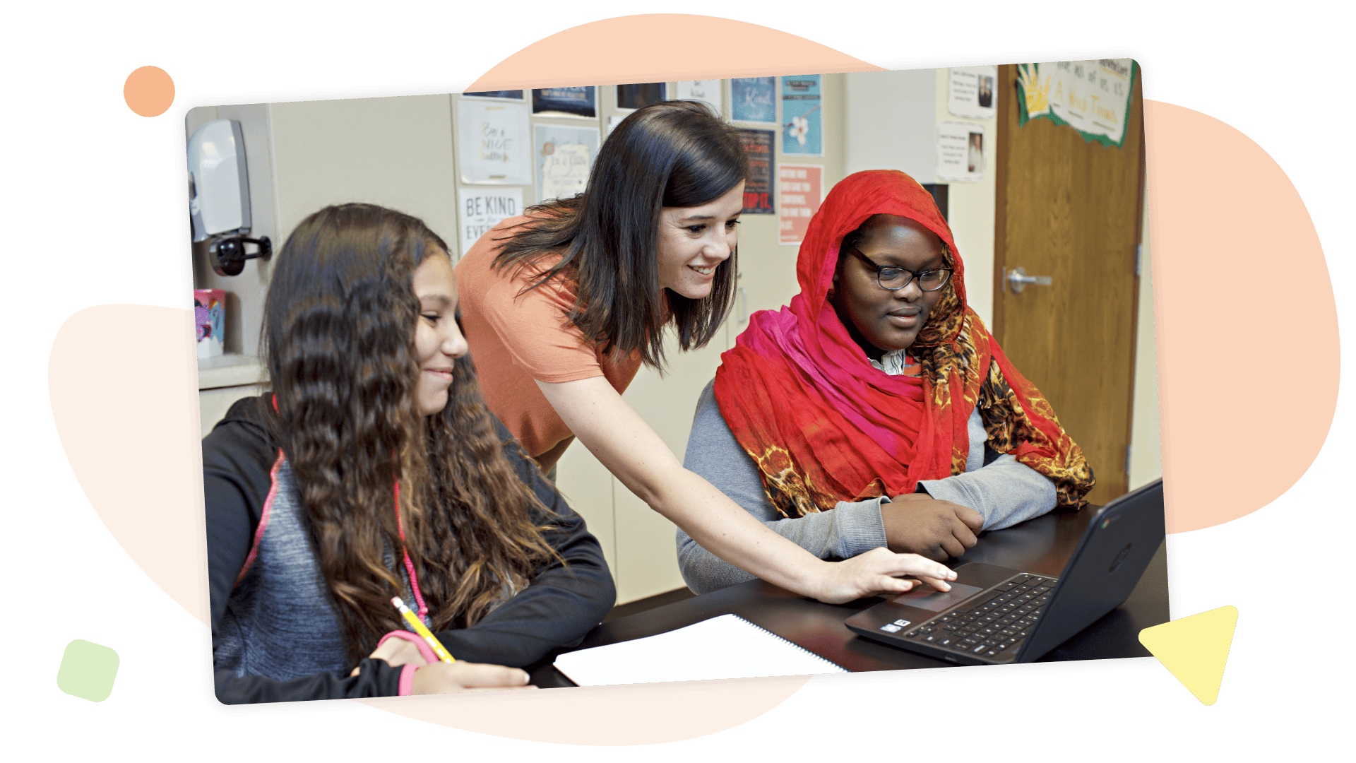 A teacher assists two diverse students with a laptop in a colorful classroom setting, focusing on coping with math anxiety.