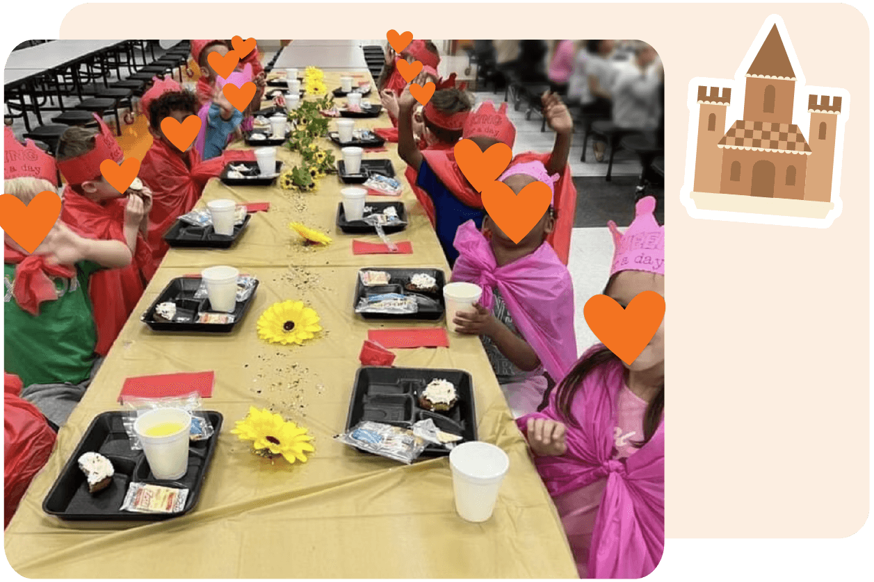 Children wearing red and pink capes and crowns sit at a long decorated table eating lunch in a cafeteria, celebrating CKLA. A castle graphic is displayed in the upper right corner, hinting at new features in their learning adventure.